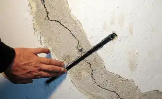 A wall with a large crack is being inspected by a professional in Chandler, AZ